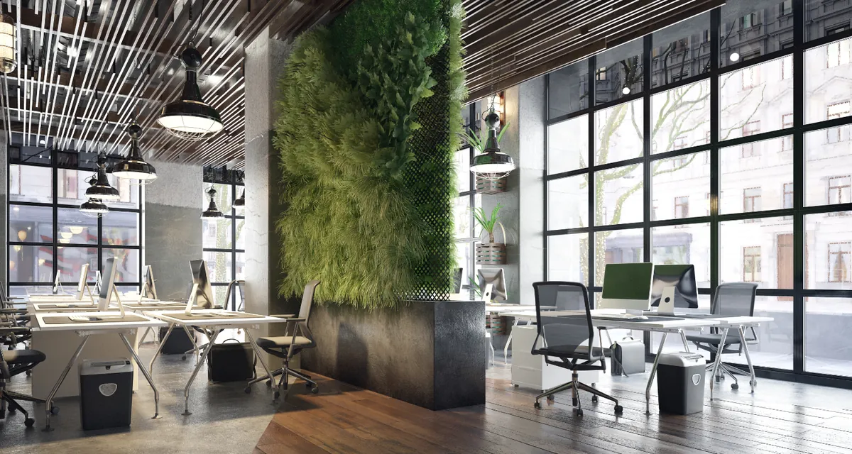 Modern open-plan office with desks and a green wall